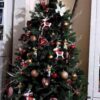 Künstlicher Weihnachtsbaum FULL 3D Finnische Fichte 210cm ist mit roten und goldenen Ornamenten verziert, befindet sich in einem Rattankorb