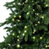 Detailná fotka vetvičiek s 3D ihličím. Okolo vetvičiek sú omotané LED vianočné svetielka svietiace v teplej bielej farbe.