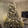 Künstlicher Weihnachtsbaum, hoch und breit grün, verziert mit weißen und silbernen Ornamenten, im Wohnzimmer