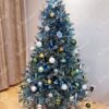 Eisgrüner künstlicher Weihnachtsbaum, verziert mit weiß-blau-goldenen Ornamenten, im Wohnzimmer
