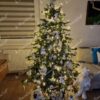 Künstlicher grüner Weihnachtsbaum, stark mit weißen Ornamenten geschmückt, im Wohnzimmer
