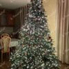 Künstlicher Weihnachtsbaum groß und massiv, dicht geschmückt mit roten und goldenen Ornamenten im Wohnzimmer