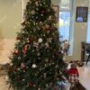 Ein großer und massiver künstlicher Weihnachtsbaum, der mit roten und goldenen Ornamenten im Wohnzimmer geschmückt