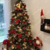 Künstlicher grüner Weihnachtsbaum mit goldenen und roten Ornamenten im Wohnzimmer