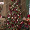 Ein großer und breiter grüner künstlicher Weihnachtsbaum, der mit roten Ornamenten im Wohnzimmer geschmückt ist