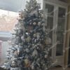 Schneebedeckter künstlicher Weihnachtsbaum mit weißen und goldenen Ornamenten im Wohnzimmer