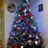Künstlicher Weihnachtsbaum groß und breit mit weißen und roten Dekorationen im Wohnzimmer