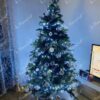 Künstlicher Weihnachtsbaum mit weißen und silbernen Verzierungen im Wohnzimmer