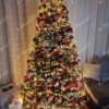 Künstlicher schneebedeckter Weihnachtsbaum mit roten und goldenen Dekorationen im Wohnzimmer