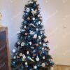 Ein künstlicher Weihnachtsbaum, geschmückt mit blauem und weißem Weihnachtsschmuck, im Wohnzimmer