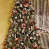 Grüner künstlicher Weihnachtsbaum, geschmückt mit rotem und natürlichem Weihnachtsschmuck, im Wohnzimmer