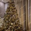 Künstlicher grüner Weihnachtsbaum, geschmückt mit weißen und goldenen Weihnachtsdekorationen, im Wohnzimmer
