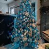 Künstlicher Weihnachtsbaum mit silbergrünen Zweigen, geschmückt mit silbernem Weihnachtsschmuck, im Wohnzimmer