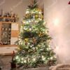 Grüner künstlicher Weihnachtsbaum, geschmückt mit goldenen Weihnachtsdekorationen mit warmweißer Beleuchtung, im Wohnzimmer
