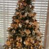 Hellgrüner künstlicher Weihnachtsbaum, geschmückt mit weißem und goldenem Weihnachtsschmuck, im Wohnzimmer