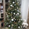 Hellgrüner künstlicher Weihnachtsbaum, geschmückt mit weißem und goldenem Weihnachtsschmuck, im Wohnzimmer