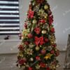 Grüner künstlicher Weihnachtsbaum, geschmückt mit rotem und goldenem Weihnachtsschmuck, im Wohnzimmer