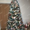 Ein hoher künstlicher Weihnachtsbaum, dicht geschmückt mit buntem Weihnachtsschmuck, im Wohnzimmer,