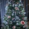 Grüner künstlicher Weihnachtsbaum, geschmückt mit weißem und rosa Weihnachtsschmuck, mit weißer Beleuchtung, im Wohnzimmer,