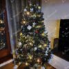 Dunkelgrüner künstlicher Weihnachtsbaum mit versilberten Zweigenden, geschmückt mit weißem und rotem Weihnachtsschmuck, im Wohnzimmer,