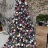 Künstlicher Weihnachtsbaum mit silbergrünen Zweigen, geschmückt mit weiß-violettem Weihnachtsschmuck, im Wohnzimme