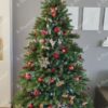 Künstlicher Weihnachtsbaum FULL 3D Finnische Fichte 210cm, ist mit roten Dekorationen verziert