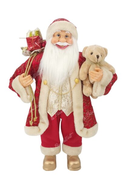 Dekoration Santa Claus Rot-Gold 60cm er trägt einen roten Mantel mit goldenen Verzierungen und einer Kette. er hat goldene Schuhe an. Er hat einen langen weißen Bart, eine Brille und hält ein Kuscheltier in der Hand.